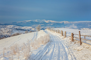 Fototapeta na wymiar Winter country landscape with timber fence and snowy road