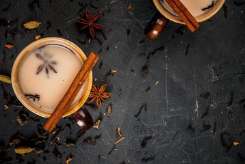 Traditional Indian masala chai tea in ceramic cups, stone table, with spices, copy space