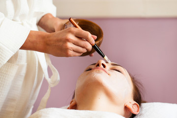Spa treatment. Beautiful woman with facial mask at beauty salon.