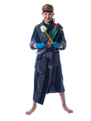 Little boy in a dressing gown and gloves holding a brush for cleaning the house and contorts funny face on a white background