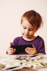 Happy successful business baby girl holding a smartphone in fron