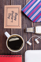 Coffee cup and greeting card. Notepad and earphones on wood. Start your day with coffee.