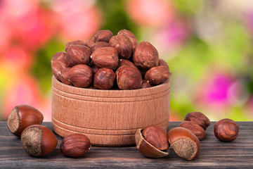 hazelnuts in a wooden bowl on  dark board with blurred garden background