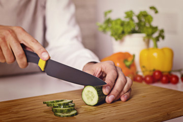 Chef's hands. Man is ready to prepare fresh salad. Chopping cucumber.