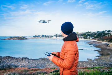 Drohnenpilot am Meer/Mann steuert eine Drohne an der Küste