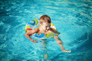 Fototapeta na wymiar Child in a swimming pool having his first swim lessons