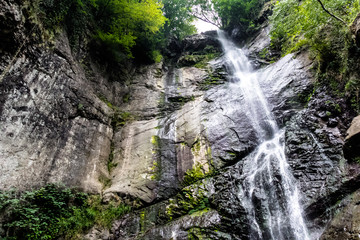 Fototapeta na wymiar Beautiful cascading full-flowing waterfall in the mountains