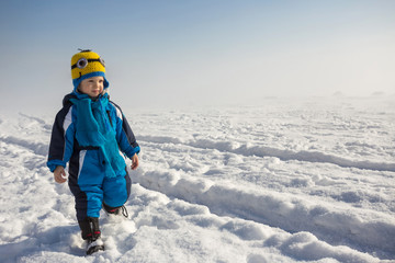Fototapeta na wymiar young boy playing on snow outdoors