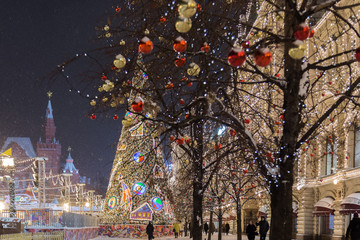 Russia, Moscow, Red Square, GUM Shopping Center on winter, snowing evening with a decorated tree in front.