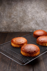 Tasty fresh newly-baked buns on a iron grid over wooden background