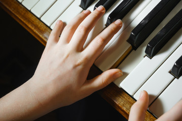 kids hands on a white piano key