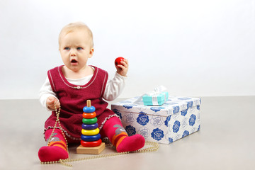 Unhappy angry little baby girl  sitting alone with presents and toys.