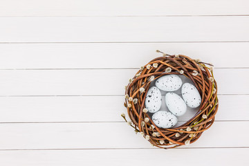 Easter background. Easter willow wreath, Easter eggs on white wooden background. Copy space, top view