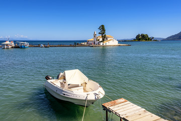 White boat moored at the pier overlooking famous Vlacherna monastery in Corfu.  Greece.