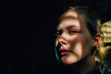Retrato de chica joven con sombras en la cara poniendo expresión de enfado