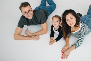 Hipster father, mother lying with baby boy on white background