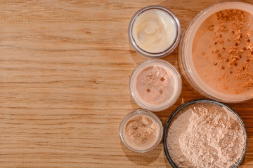 Set of decorative cosmetic powder, shimmer, eye shadow and lip balm on wooden background with copy space, beauty and makeup concept