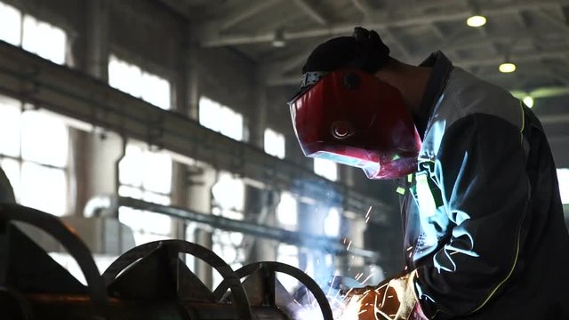 Factory. working in a huge workshop, performing welding work on the chassis high-voltage transmission lines
