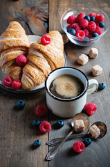 Coffee and croissants with raspberries and fruits for breakfast. Toned image, selective focus