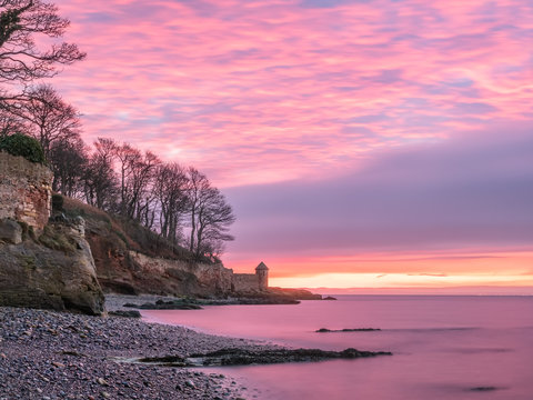 Colorful sunrise over rocky beach near Kirkcaldy, Scotland