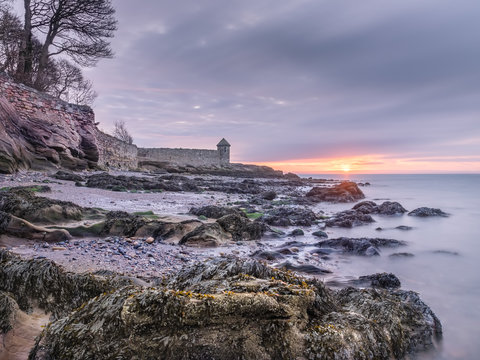 Colorful sunrise over rocky beach near Kirkcaldy, Scotland
