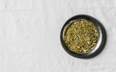 Yerba mate tea in on a metal plate against white background