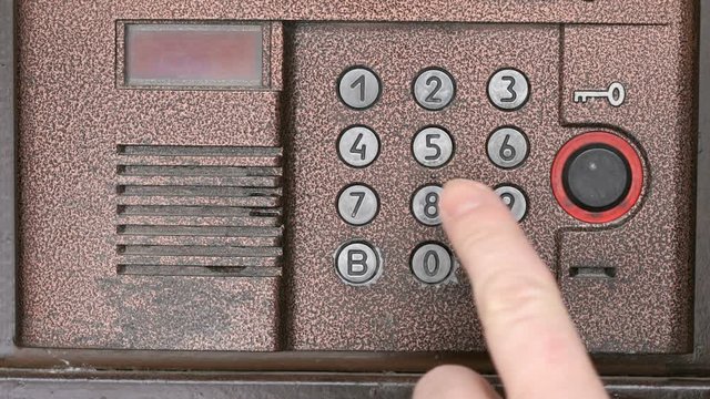 The person push the buttons on the panel of intercom system outdoors