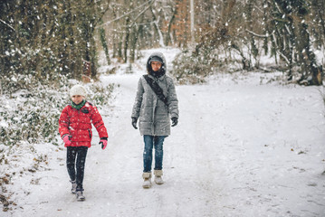 Mother with daughter hiking in snowy forest