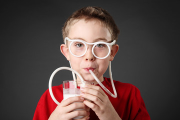 Boy drinking milk through a silly straw - obrazy, fototapety, plakaty