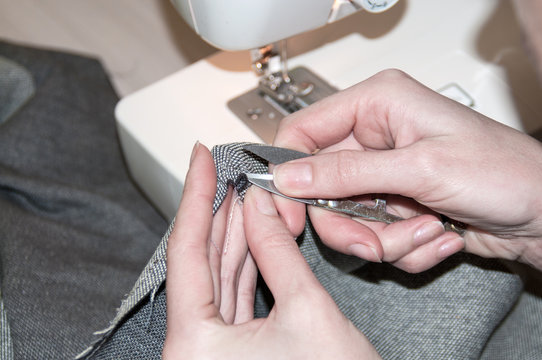 Woman rips the threads of the dress small scissors