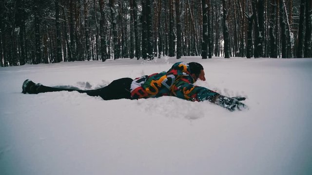 Man Jumps and Dives Headlong into the Snow and Have Fun in the Winter Pine Forest. Slow Motion