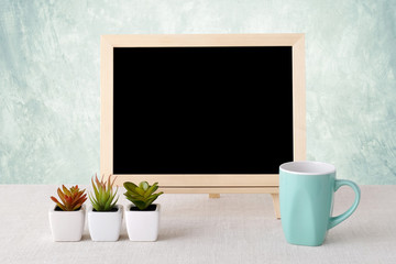 Blank chalkboard and coffee mug standing over green background