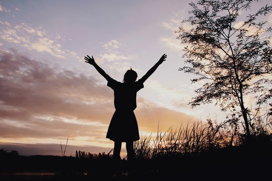 Silhouette of happy woman with sunset sky