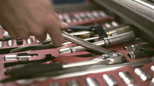Male hand pushes one of the metal tool boxes and takes the key.