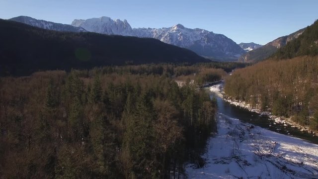 Aerial Above River in Winter Snow Dusted Mountain Forest on Sunny Day
