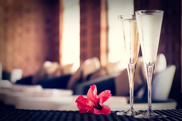 Fotobehang Two glasses of champagne with red flower in a spa lounge. Spa ti © Ekaterina_Molchanova