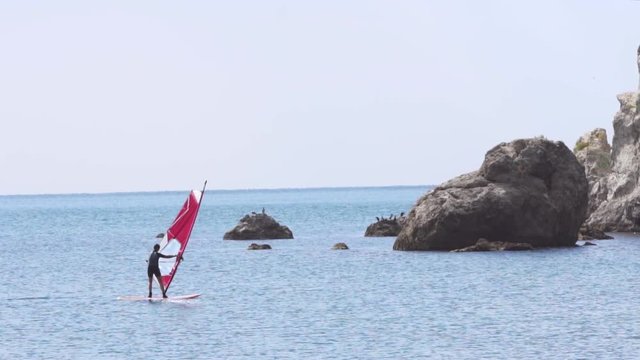 A man on windsurf conquering the waves on the sea at sunshine