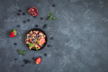 Healthy breakfast with muesli and berries on stone background. Flat lay, top view