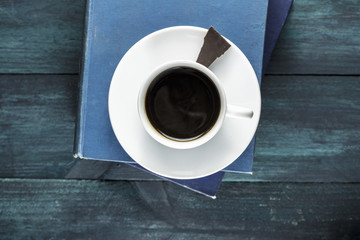 Coffee cup with old books, chocolate piece and copyspace