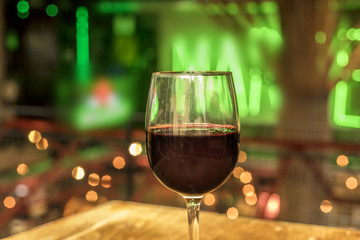 Glass of red wine on blurred lights background
