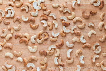 Roasted cashew nuts spread around wooden board.
