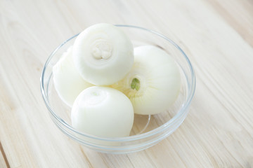 Fresh onion bulbs in a glass bowl