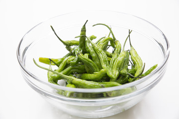 Many green chili peppers in a glass bowl	