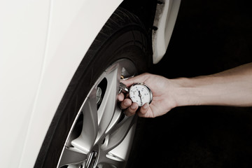 Hand of man holding gauge measurement pressure tire of car