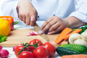 Chef cuts radishes in a vegetable salad