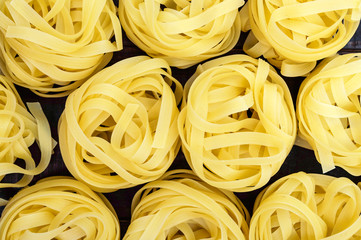 Pasta tagliatelle in the form of nests. Food background. The top view. Close-up.