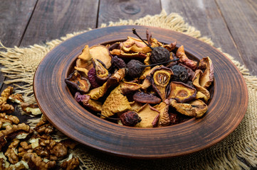 Dried fruit (apples, pears, apricots), berries and nuts in a bowl on dark wooden background. Close up. Ingredients for the winter vitamin drink, compote.