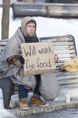 
 Young   hungry  homeless man in  winter city park looking for job
