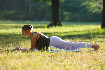 Young woman practices yoga in nature, doing exercise on core