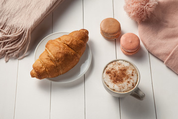 cup of cappuccino, croissant, macaroon.